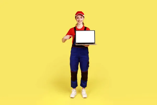 행복하게 노동자 여성이서 광고를 화면으로 컴퓨터를 작업복 모자를 사진이다 스튜디오 — 스톡 사진