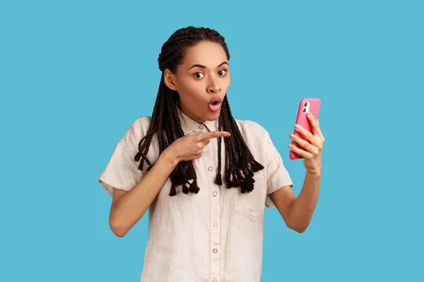 令人惊讶的黑发女士在空白的手机屏幕上点点头 惊讶于它的功能 广告技术 穿着白衬衫 室内拍摄被蓝色背景隔离 — 图库照片