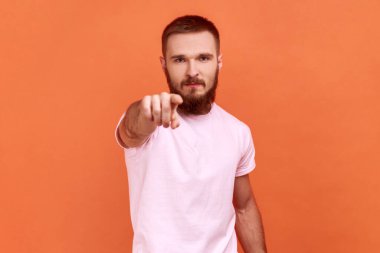 Portrait of bearded man scolding for mistake, dissatisfied with behavior, blaming showing admonishing gesture, wearing pink T-shirt. Indoor studio shot isolated on orange background.