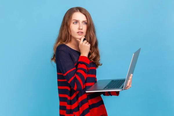 Pensiv Kvinde Iført Stribet Afslappet Stil Sweater Stående Med Bærbar - Stock-foto