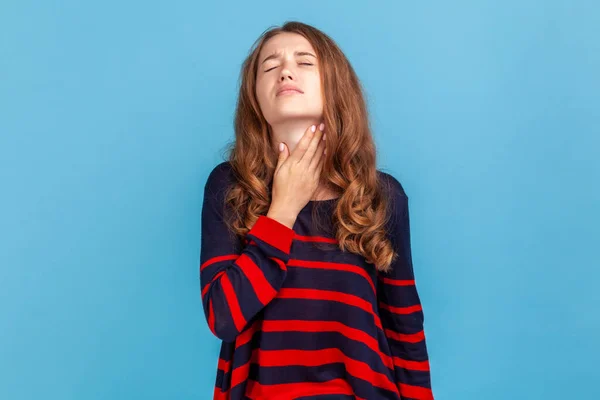 縞模様のカジュアルなスタイルのセーターを着て病気の女性の肖像画は 彼女の首に触れ 喉の痛み ウイルス感染やインフルエンザの症状に苦しんでいます 青い背景に隔離された屋内スタジオショット — ストック写真