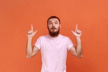 Bak, çılgın bir reklam. Reklam içeriği için boş yeri gösteren sakallı adamın portresi ve pembe tişört giyen şaşkınlığını dile getiriyor. Turuncu arka planda kapalı stüdyo çekimleri.