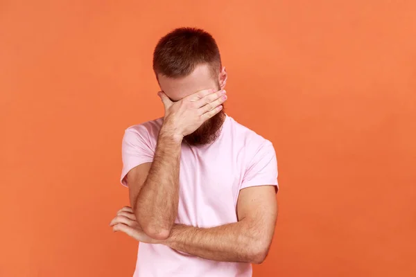 年轻大胡子男人的画像不希望看到这一点 忽视问题 躲避压力 穿着粉色T恤 在橙色背景下被隔离的室内拍摄 — 图库照片
