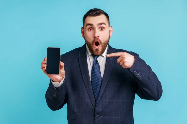 Förvånad Skäggig Man Bär Officiell Stil Kostym Pekar Finger Smartphone — Stockfoto