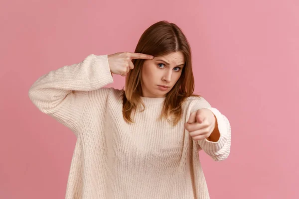 농담하시는 근처에 손가락을 카메라를 손가락을 가리키는 여성의 스웨터를 스튜디오 배경에서 — 스톡 사진