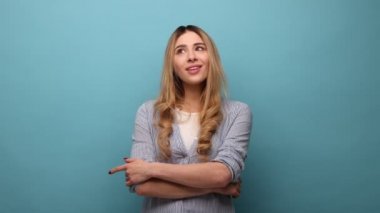 Sarışın, tapılası genç bir kadının portresi ayakta duruyor, hayal kuruyor, dilek tutuyor, sevişiyor, yanlarına bakıyor, çizgili gömlek giyiyor. Mavi arka planda kapalı stüdyo çekimi.