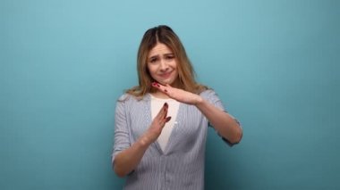 Ciddi sarışın bir kadının portresi zaman aşımı jesti, iş için daha fazla zaman, son teslim tarihi, duraklama, çizgili gömlek giymek. Mavi arka planda kapalı stüdyo çekimi.