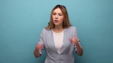 Meraklı pozitif kadının portresi dürbünlü bir jest ile ayakta duruyor, çarpıcı içeriği keşfetmek ve gözlemlemek için gülümsüyor, çizgili gömlek giyiyor. Mavi arka planda kapalı stüdyo çekimi.