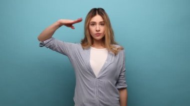 Evet, efendim. Sorumlu ciddi bir kadının portresi dalgalı saçlı selam veren komutan, itaatkar ifadeli, çizgili gömlek giyen. Mavi arka planda kapalı stüdyo çekimi.