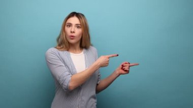 Çılgın bir reklam. Şaşırmış bir kadın yan fotokopi alanını işaret ediyor, reklam metinleri için boş duvara dikkat çekiyor, çizgili gömlek giyiyor. Mavi arka planda kapalı stüdyo çekimi.