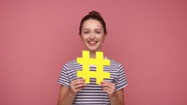 İnternet popülerliği. Elinde hashtag sembolü olan mutlu, güzel bir kadın sosyal ağda viral konuları tanıtıyor, Palm 'da kopya alanı sunuyor. Pembe arka planda kapalı stüdyo çekimleri.