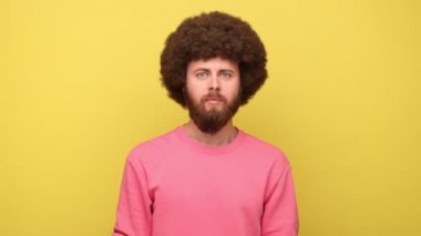 Kimseye söylemem, söz veriyorum. Sakallı, Afro saç stili, ağzı sıkı, ağzı sıkı, fermuarlı dudaklı, pembe kazak giyen bir adam. Sarı arka planda kapalı stüdyo çekimleri