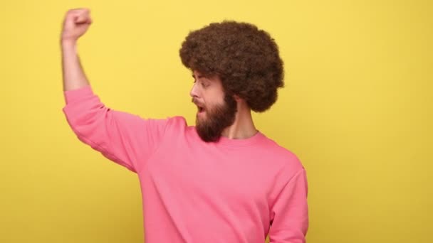 Bearded Man Med Afro Frisyr Visar Biceps Pekar Muskler Stolt — Stockvideo