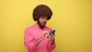 Uzun saatler boyunca cep telefonu kullanan sakallı bir adam gözlerinin acıdığını, gözlüğünü çıkardığını ve pembe kazak giydiğini hisseder. Sarı arka planda kapalı stüdyo çekimleri.