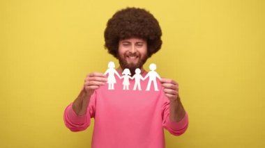 Afro saçlı sakallı adam kağıt zincirli insanlar el ele tutuşuyor, mutlu aile kavramı, babalık, çocukluk, pembe kazak giyiyor. Sarı arka planda kapalı stüdyo çekimleri.