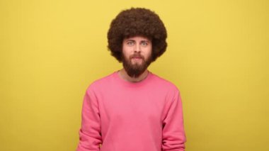 Hipster adam elinde uçak, pasaport ve kartta satılık yazı, yurtdışına seyahat hayali, düşük maliyetli, pembe kazak giyiyor. Sarı arka planda kapalı stüdyo çekimleri.