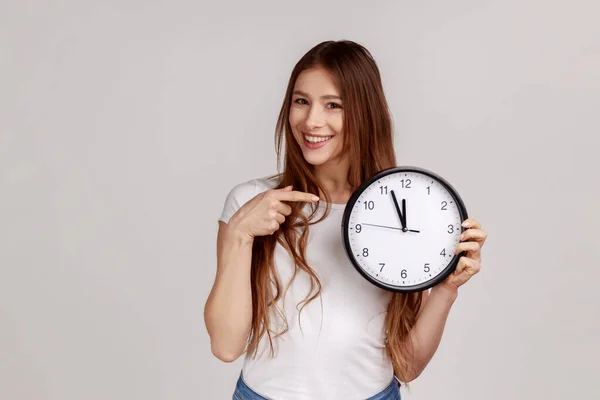 커다란 시계를 미소로 카메라를 티셔츠를 매력적 여성의 은회색 배경에 고립되어 — 스톡 사진