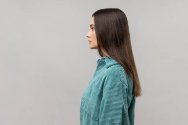 Geleceğe bakan otoriter bir kadının portresinin yan görüntüsü, kendine güvenen, ciddiyetini ifade eden, günlük tarz ceket giyen. Gri arka planda izole edilmiş kapalı stüdyo görüntüleri.