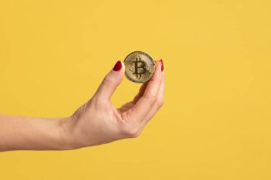 Altın Bitcoin 'in el ele tutuşması, reklam btc madeni para, kripto para, dijital para, elektronik yatırım için kopyalama alanı. Sarı arka planda kapalı stüdyo çekimleri.