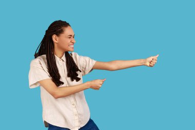 Profil portresi güçlü, kendine güveni olan, rastalı, görünmez ipini çeken, inatçılığını ve liderlik vasıflarını gösteren, beyaz gömlek giyen bir kadın. Mavi arka planda kapalı stüdyo çekimi.