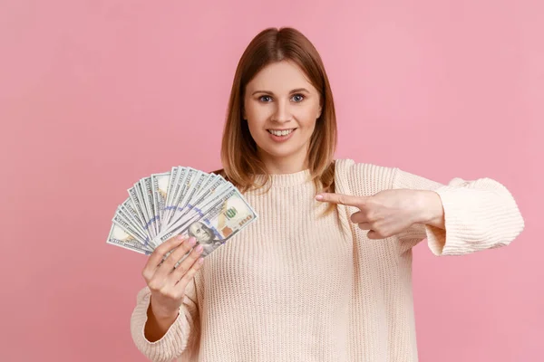 지폐를 가리키면서 모습으로 카메라 스웨터 아름다운 금발의 여인의 모습이다 스튜디오 — 스톡 사진