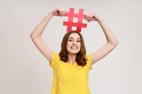 Happy Teen Girl Toothy Smile Yellow Shirt Holding Red Hashtag — Stock Photo, Image