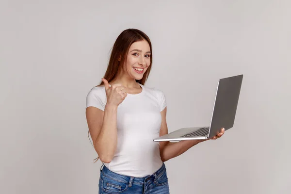 Portrait Pleased Young Woman Holding Laptop Showing Thumbs Looking Camera — kuvapankkivalokuva