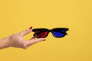 Profil yan görüntüsü kadın el ele tutuşması ve sinemada film izlemek için 3D gözlük gösterilmesi. Sarı arka planda kapalı stüdyo çekimleri.