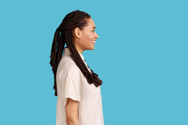 黑发的快乐女人的侧面肖像 有着积极乐观的情绪和迷人的微笑 穿着白衬衫 室内拍摄被蓝色背景隔离 — 图库照片