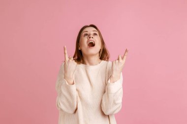 Şuraya bak, reklam alanı. Şaşırmış sarışın kadının portresi şaşırmış görünüyor ve beyaz süveter giyip fotokopi alanını işaret ediyor. Pembe arka planda kapalı stüdyo çekimleri.