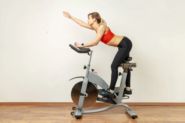 Side View Portrait Slim Woman Riding Exercise Bike Raised Arm — Stock fotografie