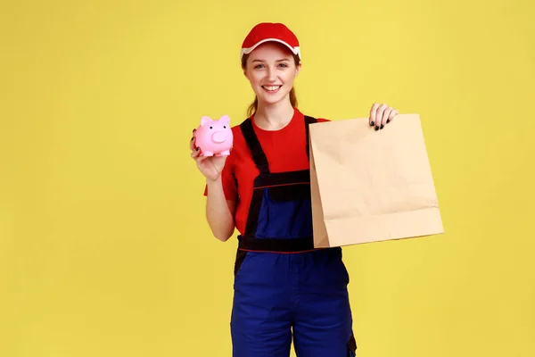 Portrait Delivery Woman Holding Paper Parcel Piggybank Looking Camera Happy — Stockfoto