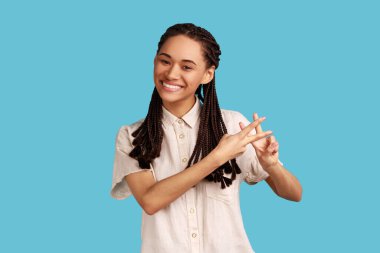 Olumlu popüler kadın blogcu parmaklarıyla hashtag işareti yapıyor, kameraya gülümseyerek bakıyor, sosyal ağlardaki yazıları etiketliyor, etiket öneriyor. Mavi arka planda kapalı stüdyo çekimi.