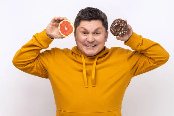 Портрет Положительного Смешного Человека Показывающего Сладкий Пончик Свежий Сочный Грейпфрут — стоковое фото