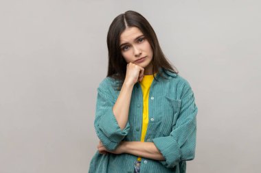 Sıkılmış genç bir kadının portresi kasvetli depresif bir ifadeyle can sıkıcı bir hikaye dinlerken sohbete kayıtsız kalmak, fikir yoksunluğu. Gri arka planda izole edilmiş kapalı stüdyo görüntüleri.