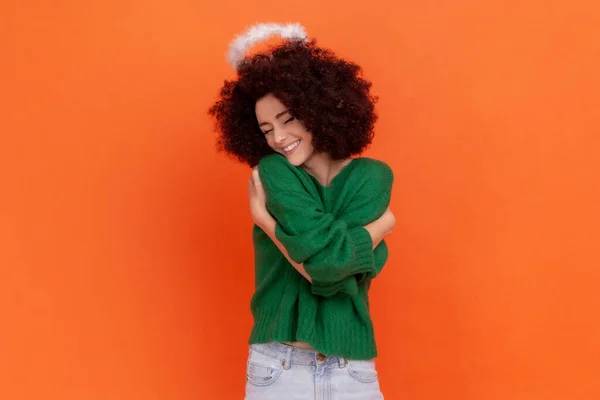 快乐而满意的女人 穿着绿色休闲装 头戴轻快的头巾 抱着自己 表达爱意 拥抱他人 在橙色背景下被隔离的室内拍摄 — 图库照片
