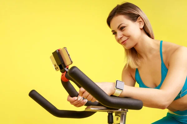 Closeup Athletic Woman Riding Exercise Bike Using Her Mobile Phone — Stock Photo, Image