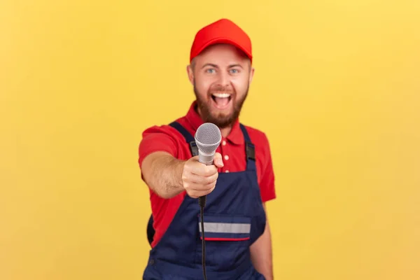 Retrato Homem Trabalhador Barbudo Animado Uniforme Azul Tampa Oferecendo Microfone — Fotografia de Stock