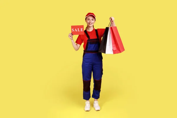 Elinde Alışveriş Poşetleri Olan Elinde Tulum Kırmızı Şapkalı Satılık Kartlarla — Stok fotoğraf