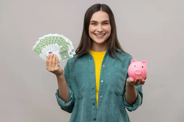 Portret Uśmiechniętej Afirmatywnej Kobiety Trzymającej Dużą Sumę Banknotów Euro Skarbonki — Zdjęcie stockowe