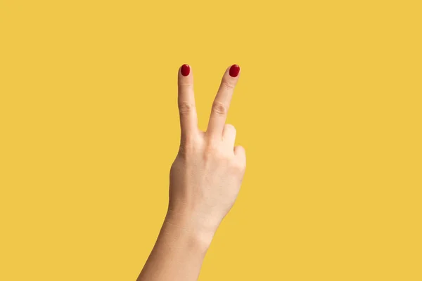 勝利を示す女性の手のプロフィール側のビューのクローズアップ 平和サインまたは番号2指で 黄色の背景に隔離された屋内スタジオショット — ストック写真
