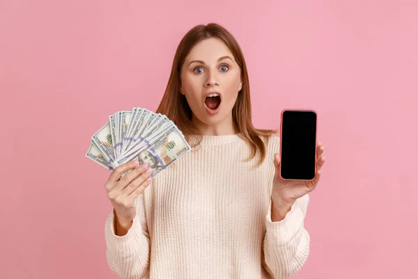 Portret Zszokowanej Blondynki Trzymającej Banknoty Dolarowe Smartfona Pustym Ekranem Zakładami — Zdjęcie stockowe