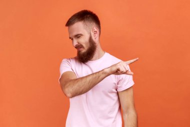 Sakallı bir adamın portresi. Parmakla işaret ediyor, sipariş veriyor ve alıngan görünüyor. Patron işten çıkıyor, çıkışı gösteriyor, pembe tişört giyiyor. Turuncu arka planda kapalı stüdyo çekimleri.