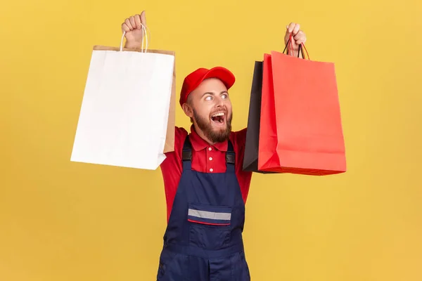 Porträt Eines Zufriedenen Bärtigen Zustellers Blauer Uniform Der Papiereinkaufstüten Der — Stockfoto