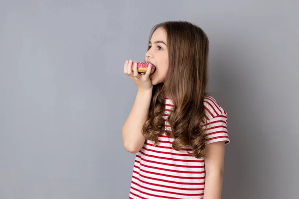 Portrait Hungry Charming Little Girl Wearing Striped Shirt Standing Biting — Stock Photo, Image