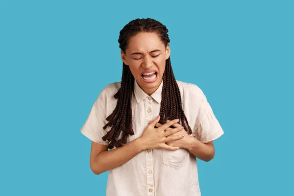 忧心忡忡的女人把双手放在胸前 患有心脏病 有健康问题 有尴尬的表情 需要医生的帮助 室内拍摄被蓝色背景隔离 — 图库照片