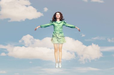 Uzun, mutlu, sakin, fırfırlı elbiseli, havada kanat gibi havada asılı duran, trambolin atlayan ya da gökyüzünde uçan bir kız. kolaj kompozisyonu bulutlu mavi gökyüzünde