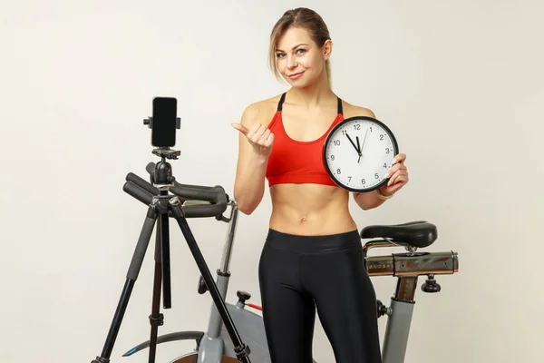 Sportliche Frau Mit Wanduhr Der Hand Und Handy Auf Stativ — Stockfoto