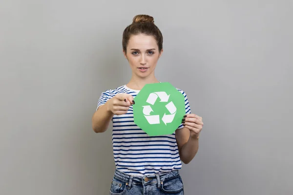 Portrait Woman Wearing Striped Shirt Holding Green Recycling Sign Pointing — 스톡 사진