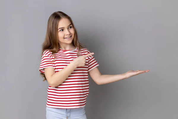 Portrait Little Girl Wearing Striped Shirt Presenting Advertising Area Her — Stockfoto